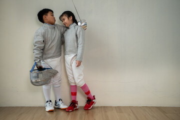 Before the tournament day, a boy and girl dressed in fencing gear are rehearsing in gym