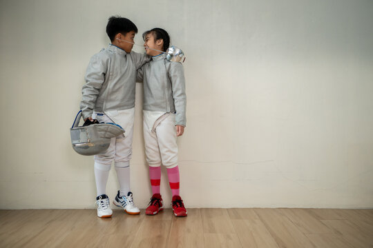 Before the tournament day, a boy and girl dressed in fencing gear are rehearsing in gym