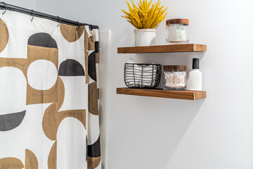 Modern vacation rental bathroom with wooden floating shelves, toiletries, and a shower curtain