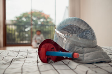 Before the tournament day, a boy dressed in fencing gear are rehearsing in gym