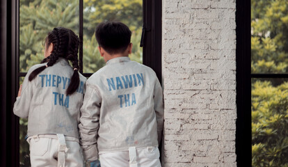 Before the tournament day, a boy and girl dressed in fencing gear are rehearsing in gym