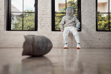 Before the tournament day, a boy dressed in fencing gear are rehearsing in gym