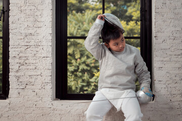 Before the tournament day, a boy dressed in fencing gear are rehearsing in gym