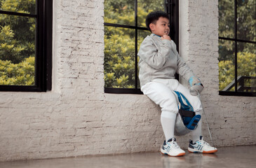 Before the tournament day, a boy dressed in fencing gear are rehearsing in gym