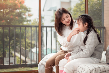 A girl in fencing gear with their mother preparing food and sports equipment