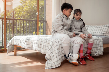 A girl and boy in fencing gear resting before practicing fencing