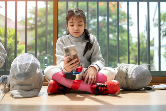 A girl in fencing gear resting before practicing fencing in preparation - Powered by Adobe