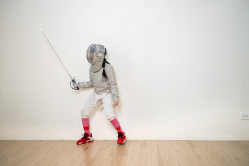 Before the tournament day, a boy and girl dressed in fencing gear are rehearsing in gym