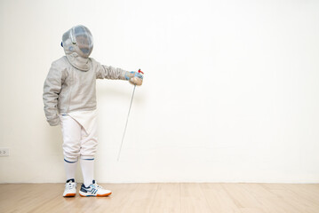 Before the tournament day, a boy dressed in fencing gear are rehearsing in gym