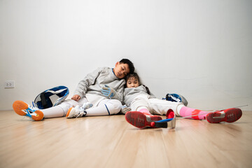 A girl and boy in fencing gear is sitting and rest on the sidelines, exhausted from the training...
