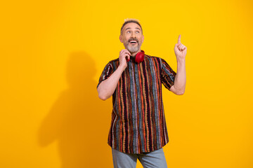 Charming mature man with trendy fashion showcasing dynamic gestures against vibrant yellow backdrop