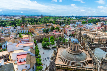 Panoramic aerial view of Seville’s historic center with Cathedral dome, Alcazar walls, and colorful rooftops surrounded by greenery