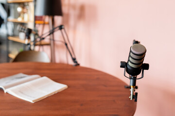 Podcast recording setup features a microphone and a notebook on a wooden table in a cozy studio...