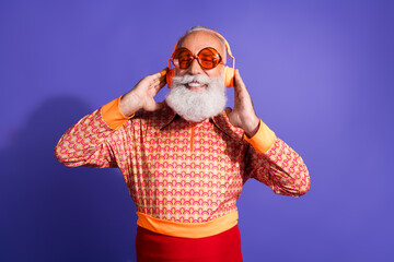 Charismatic mature man enjoying music in vibrant retro style outfit showcasing joyful and trendy...