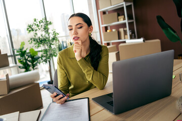 Fashion designer working in a stylish studio with laptop and smartphone during a productive workday