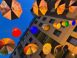 Illuminated city, street decorated with umbrellas.