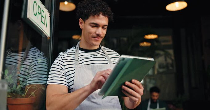 Waiter, door and typing on tablet in restaurant for seating plan, welcome and order management. Barista, small business and man with digital app at cafe entrance for hospitality and customer service