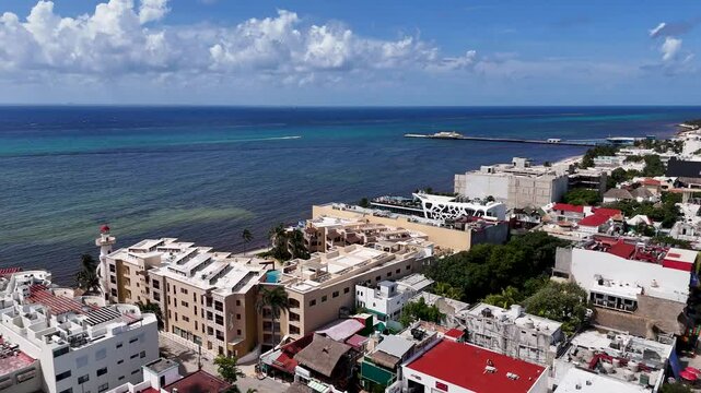 Aerial drone view of landscape in Playa del carmen with blue Caribbean Sea and buildings rooftop in the downtown area on a sunny day with blue sky and few clouds