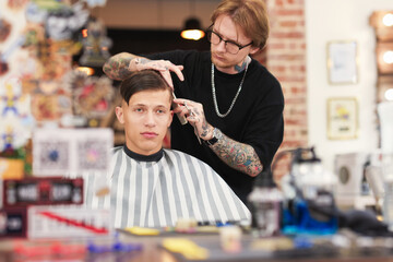 Professional barber making stylish haircut in barbershop