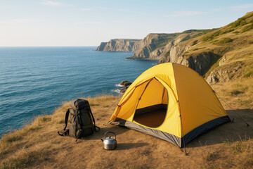 Yellow tent backpack and kettle on cliff overlooking blue ocean and rocky coastline
