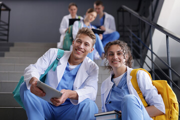 Group of medical students in uniforms on stairs indoors, low angle view