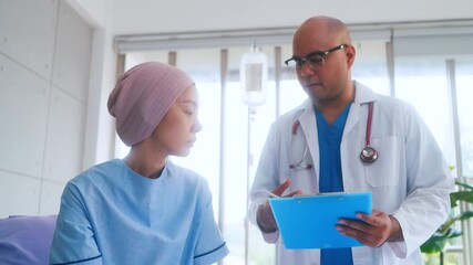Asian woman patient describes her symptoms to an oncologist while sitting on a bed and looking at a man doctor in a lab coat in a hospital ward, health and medical care concept - Powered by Adobe