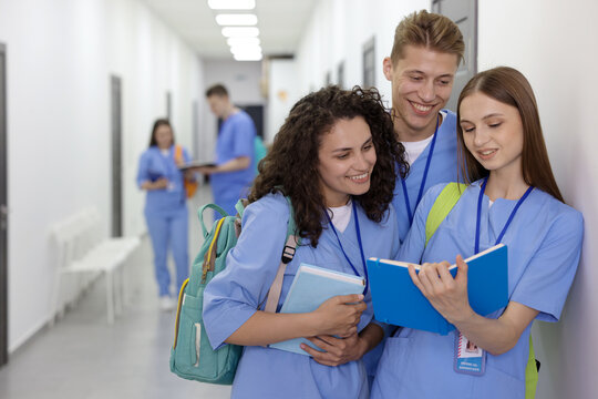 Medical students in uniforms studying together indoors, selective focus