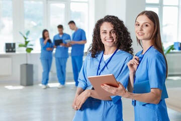 Medical students in uniforms with tablet and laptop indoors, selective focus