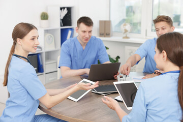 Medical students in uniforms studying together at table indoors