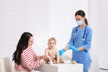 Obraz premium Mother and her cute baby having appointment with pediatrician in clinic. Doctor vaccinating child