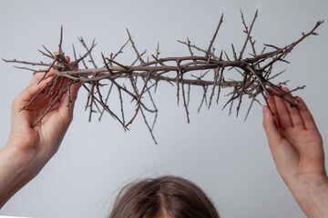 Conceptual image: lost childhood, broken dreams, fear and pain. A child puts a crown of thorns on...