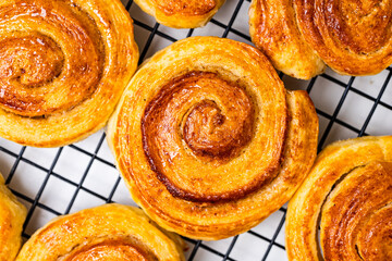 Delicious homemade cinnamon puff pastry buns in the shape of a roll or snail on a black grill....