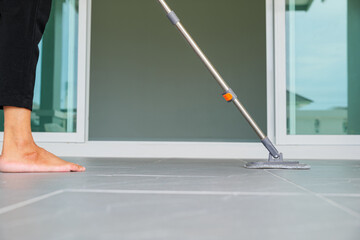 Woman mops the indoor floor, cleaning the front area of her home with a mop and rag. Housewife dedicated to maintaining cleanliness. Represents professional housekeeping and house maintenance concepts