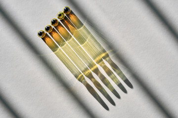 Ampoules with a medical drug on a gray background with stripes of shadows.