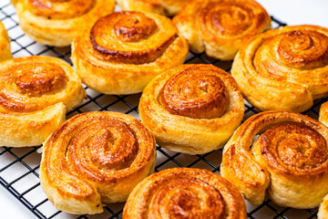Delicious homemade cinnamon puff pastry buns in the shape of a roll or snail on a black grill. Close-up.