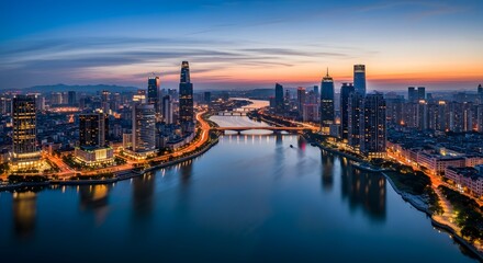 Obraz premium Panoramic cityscape at dusk with illuminated skyscrapers reflecting in a calm river against a twilight sky showcasing urban architecture