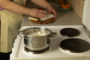 semi-melted butter in a saucepan on the stove, in the background the hands of a senior woman