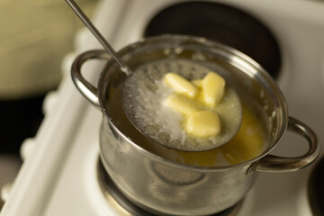 stirring sweet cream ghee in a saucepan on the stove