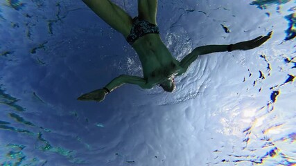 man swimming in pool, view from bottom up. Outdoor pool illuminated by sunlight - Powered by Adobe