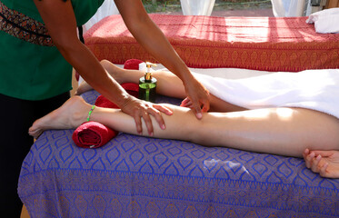 strong hands of a Thai masseuse massaging the pulp of a young woman during a draining and...
