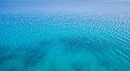 A tranquil expanse of vibrant turquoise ocean stretches to the horizon under a clear sky