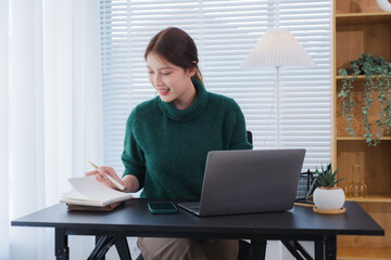 Focused at Desk: A woman engrossed in her work at a contemporary desk, notebook, laptop, a scene of...