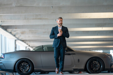 Rich business man near a luxury car. Rich businessman in suit outdoors. Successful rich business...
