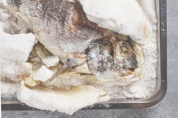 Baked Dorado fish, in salt on a baking sheet, top view, homemade, no people.
