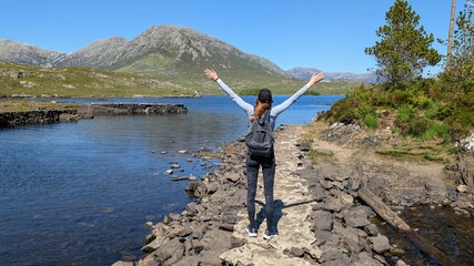 Hiker girl with hands up at twele pines island, Connemara, Galway, Ireland, backpacker adventure...