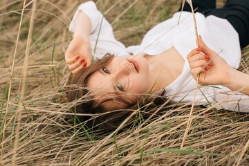 Model relaxing in dry grass during photoshoot in nature