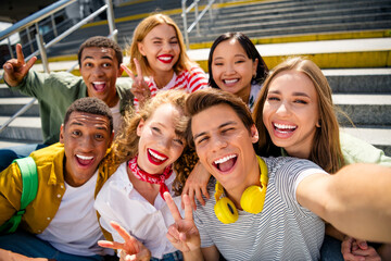 Joyous students taking a selfie together outdoors during summer in the city as they enjoy their vacation