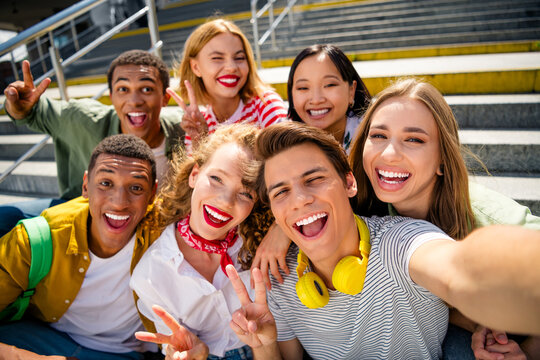 Joyous students taking a selfie together outdoors during summer in the city as they enjoy their vacation