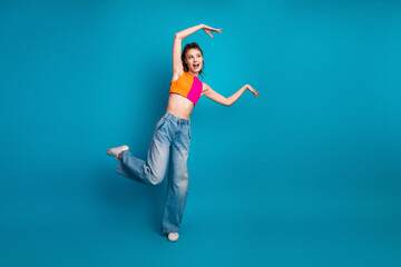 Young woman in colorful casual attire posing creatively against vibrant blue background with an...