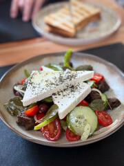 Traditional Greek Salad with feta cheese, cucumbers, tomatoes, paprika, olives and onion in a plate...